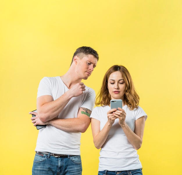 jealous boyfriend spying his girlfriend watching her phone against yellow background 23 2148056427
